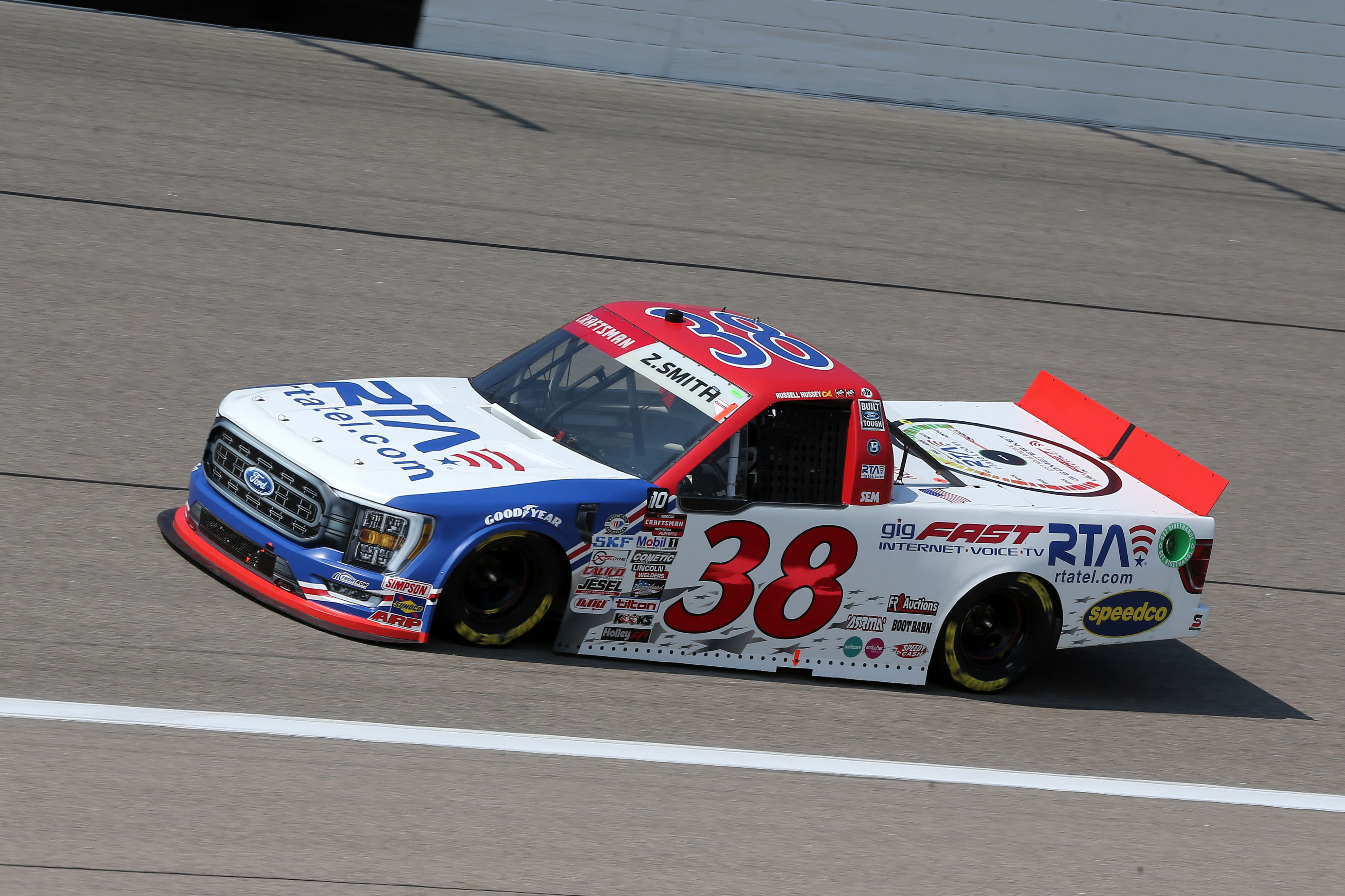 #38 Ford F-150 NASCAR truck in motion at speed — gigFAST Internet and RTA rtatel.com livery clearly visible on the side
