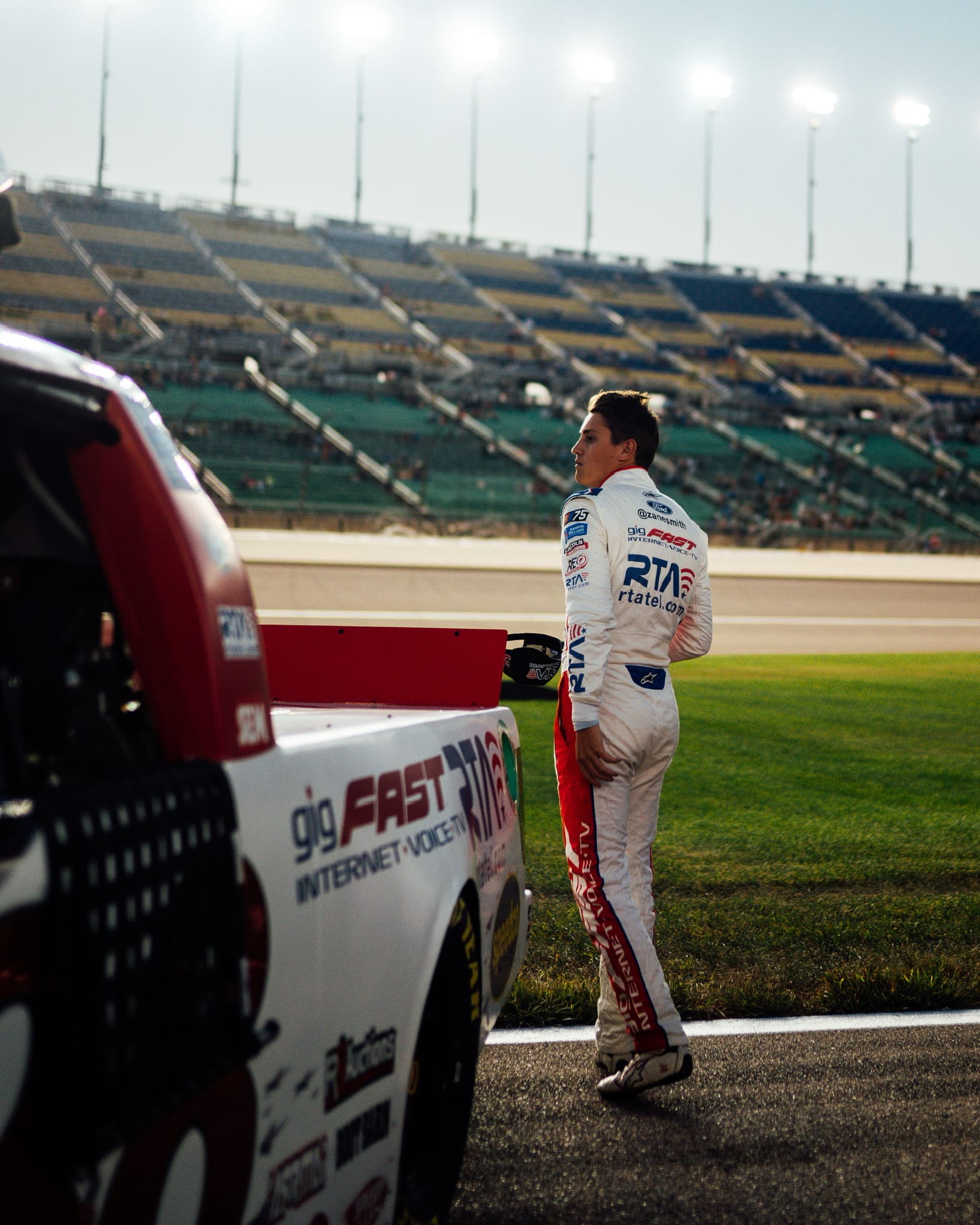 Zane Smith at trackside with gigFAST truck visible behind, golden hour editorial shot